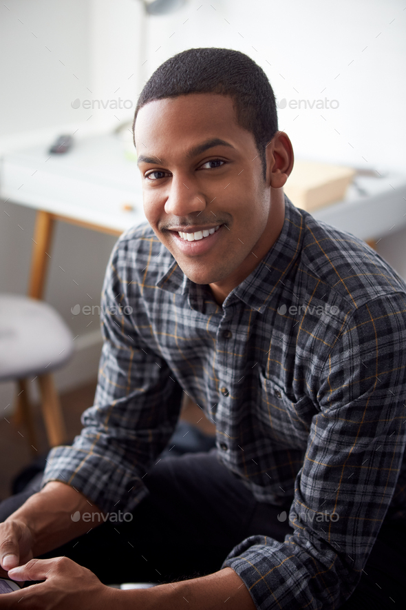 Portrait Of Smiling Male Student In Bedroom Of Rented House
