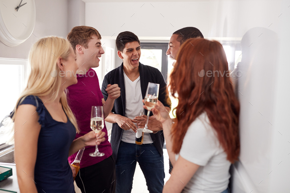 Group Of College Students In Shared House Kitchen Hanging Out And Drinking Together