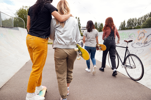 Rear View Of Female Friends With Skateboards And Bike Walking Through Urban Skate Park - Stock Photo - Images
