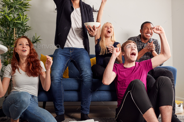 Group Of College Friends Celebrating Whilst Watching Sports Game On TV In Shared House