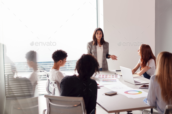 Female Boss Gives Presentation To Team Of Young Businesswomen Meeting  Around Table In Modern Office Stock Photo by monkeybusiness