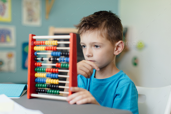 Thinking schoolboy learning maths with an abacus - Stock Photo - Images