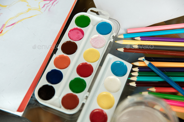 Used water-color paint-box, brush, pencils and pastels on wooden with paper  Stock Photo by master1305