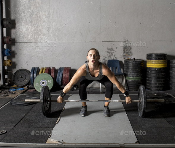Young strong woman lifting weights in gym. Stock Photo by wollwerth