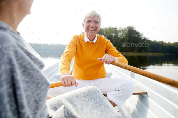 Excited man rowing with oars on boat