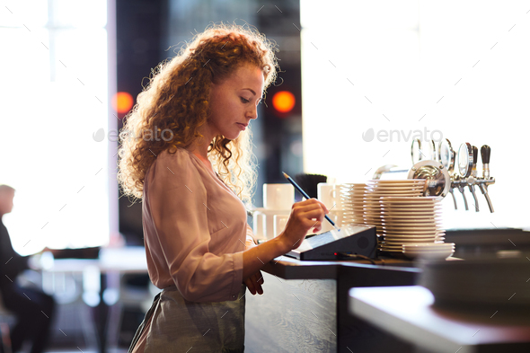 Pensive waitress adding order in restaurant POS - Stock Photo - Images