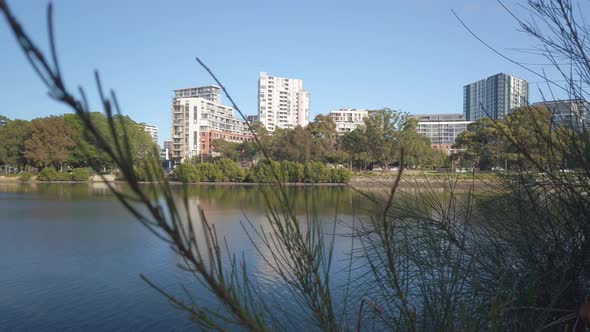 Beautiful and calm river in the morning with waterfront apartment building in the background. Slidin alt