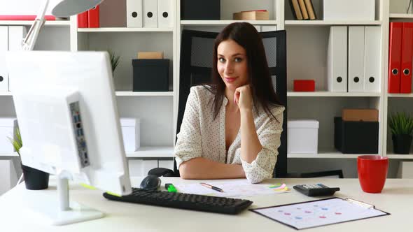 Businesswoman Leaning Her Chin and Looking at Camera in Office