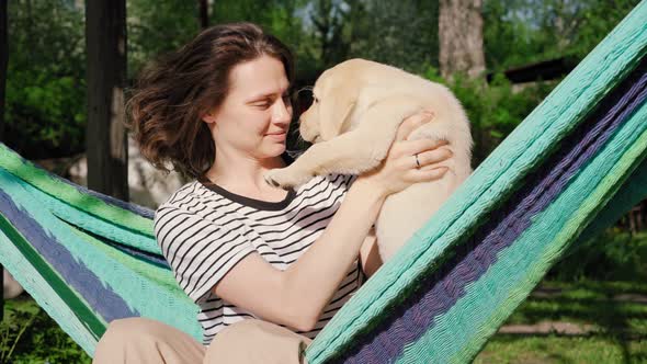Young Woman Having Fun Playing with Her Little Cute Labrador Puppy alt