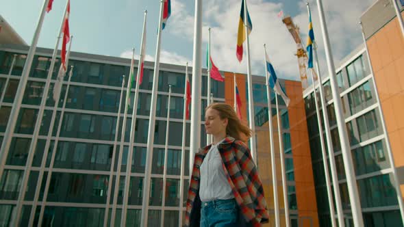 Woman Walks and Talks By Phone in European Parliament with Flags of EU Countries