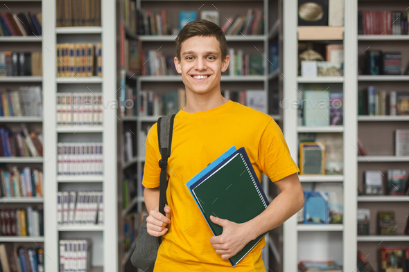 Handsome young guy standing in library, bookshelves background Stock ...