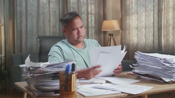 Fat Asian Man Stretching While Working Hard With Documents At The Office alt
