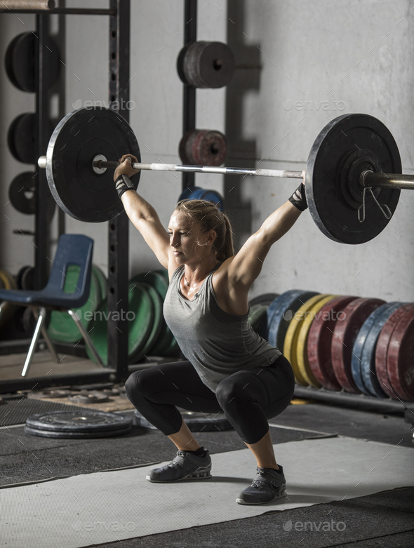 Young, strong, female weight lifter practicing snatch in weight
