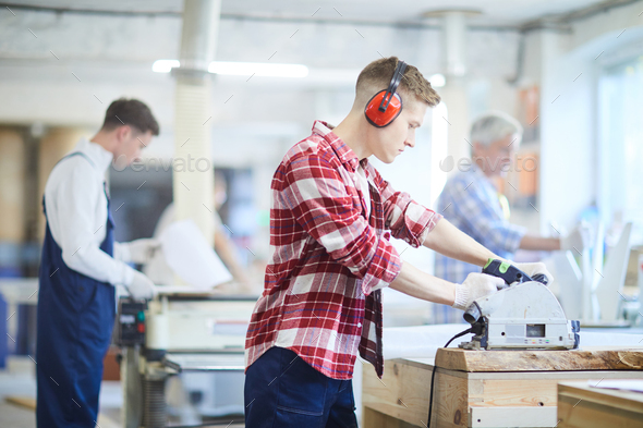 Concentrated carpenter in ear protectors working with circular saw