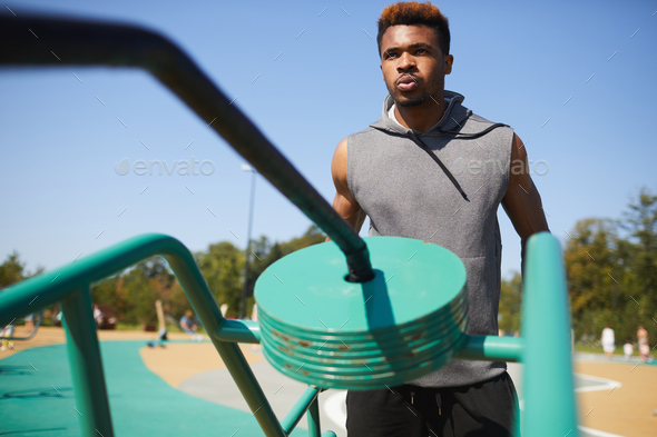 Black man breathing out while training with workout equipment