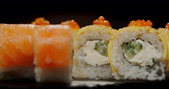 Sushi Sprinkled With Red Caviar Rotates On A Black Board