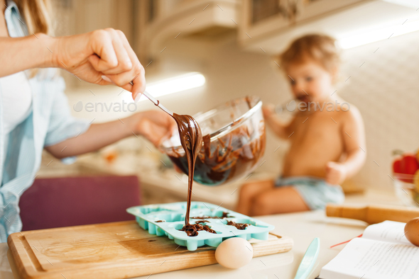 Mother and kid cooking and tastes melted chocolate - Stock Photo - Images