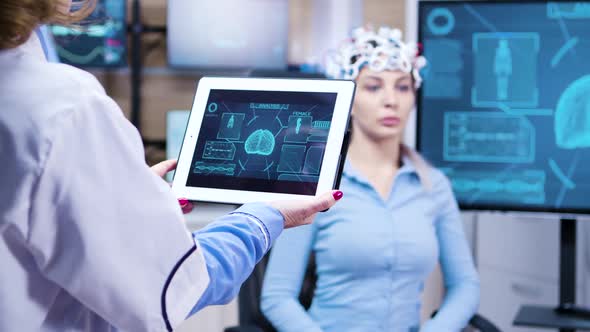 Middle Age Female Doctor Holding Tablet with Patient Brain Activity alt