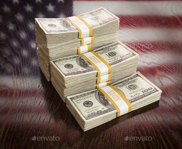 Thousands of Dollars Stacked with Reflection of American Flag on Wooden Table. - Stock Photo - Images