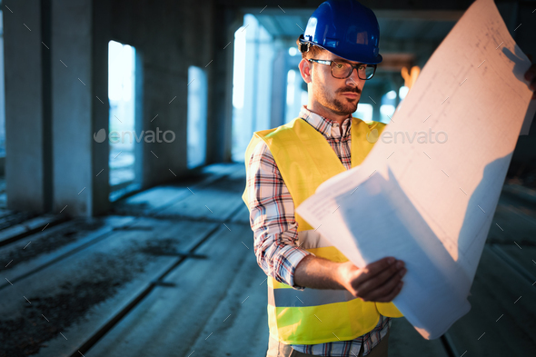 Picture of construction site engineer looking at plan - Stock Photo - Images