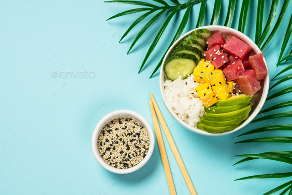 Download Tuna poke bowl with rice, avocado, mango and cucumber on blue Stock Photo by Nadianb