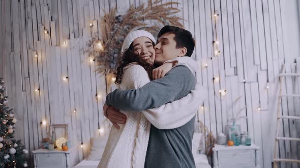 Portrait of Two Young Lovers Inside, Warmly Embracing Around Christmas. alt
