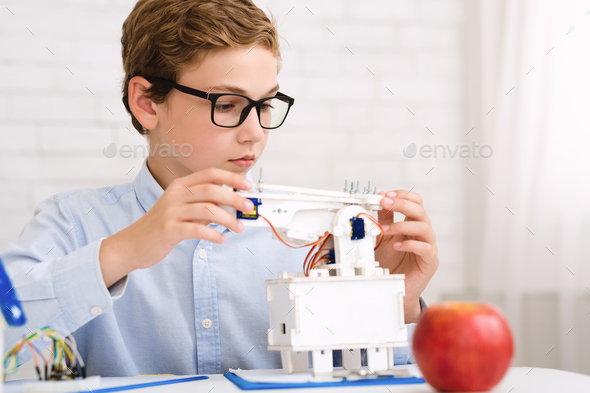 Smart schoolboy constructing electronic robot at stem class