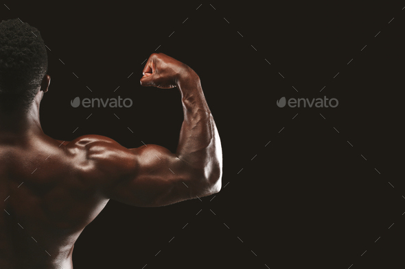 Strong biceps of afro bodybuilder on black background - Stock Photo - Images