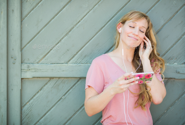 Young Adult Woman Listening To Music with Earphones on Her Smart Phone