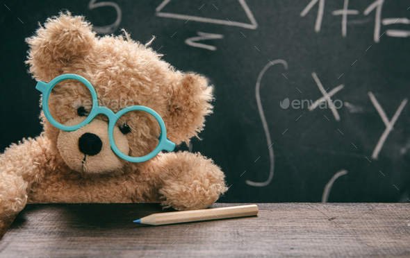 Math test. Cute teddy wearing glasses and black chalkboard
