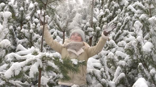 Beautiful Woman Standing Among Snowy Trees in Winter Forest and Enjoying First Snow