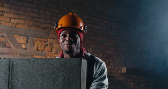 Happy Black Builder Playing Behind Brick Wall alt