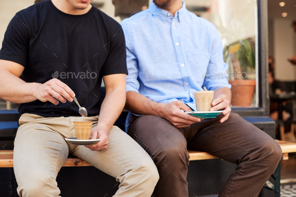 Close Up Of Two Men Sitting Outside Coffee Shop Drinking Coffee