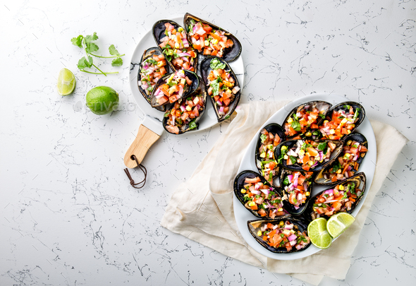 Big mussels, choros zapatos seasoned with purple onion, tomatoes, corn and lemon - Stock Photo - Images