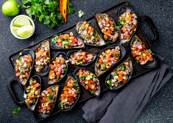 Big mussels, choros zapatos seasoned with purple onion, tomatoes, corn and lemon - Stock Photo - Images