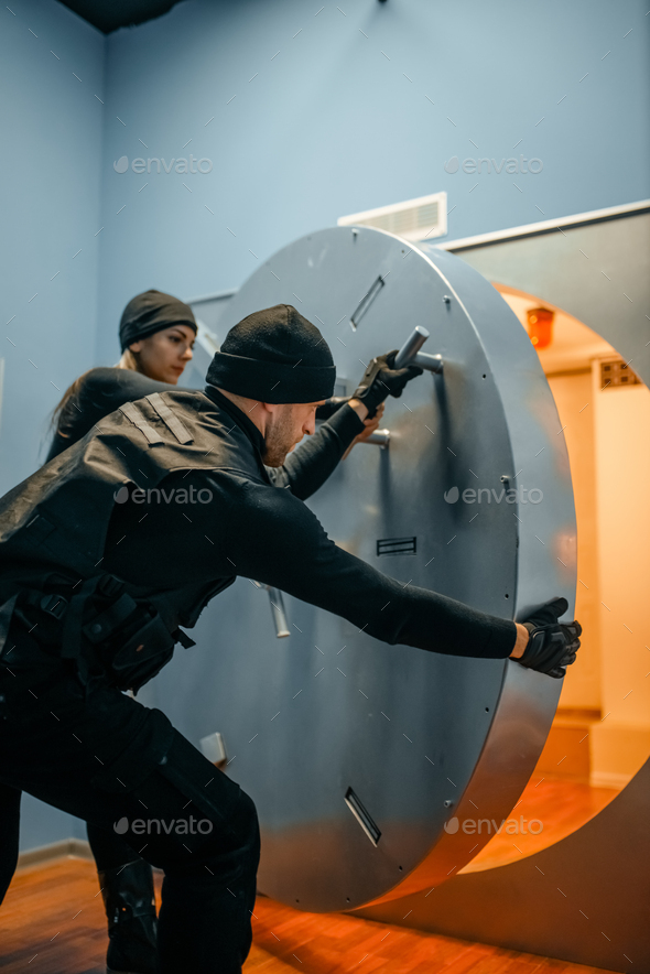 Robbers in black uniform opening vault door