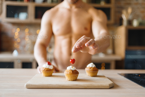 Man with naked body cooking cakes with cherry