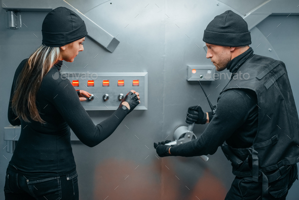 Two robbers in uniform trying to break vault lock