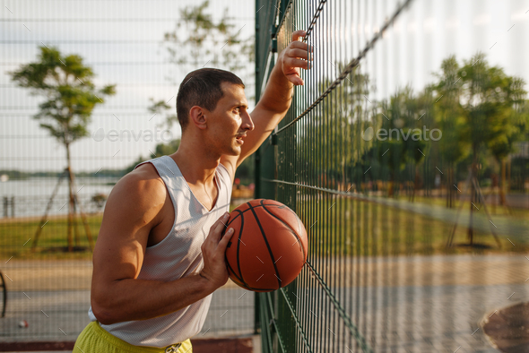 Basketball player standing at the mesh fence