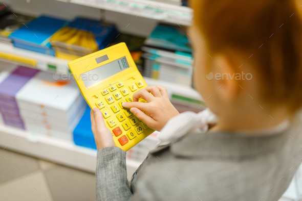 Schoolgirl holds calculator, stationery store