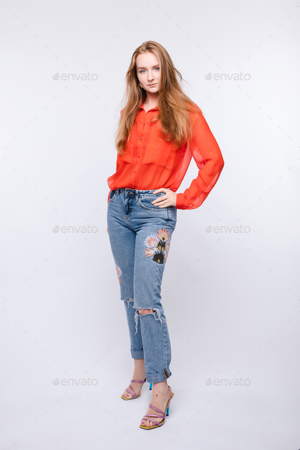 Girl in red blouse and jeans posing on isolated background