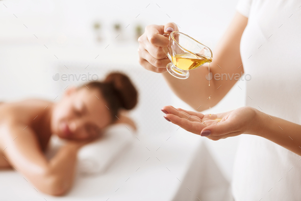 Masseur pouring massage aroma oil on hand - Stock Photo - Images