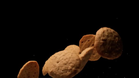 Slow motion cookies flying on black background. alt