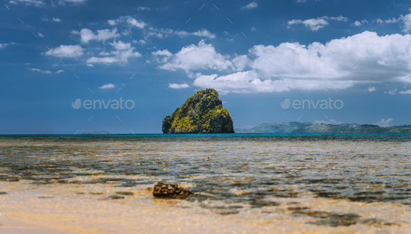 Panoramic low angle shot of beautiful secluded cliff island in open ocean surrounded by turquoise - Stock Photo - Images