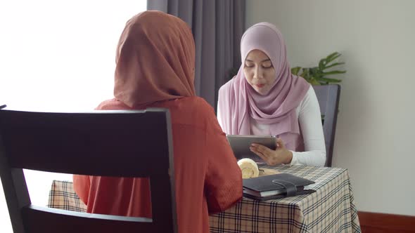 Young muslim working woman discussing with friend in coffee shop