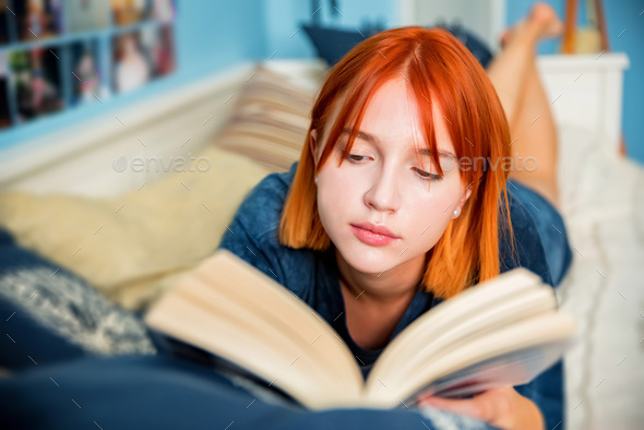Pretty Red Haired Teenage Girl Reads Book In Her Room Stock Photo
