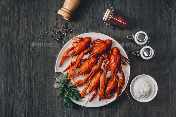 Boiled big red fresh crawfish in white plate with green herbs - Stock Photo - Images