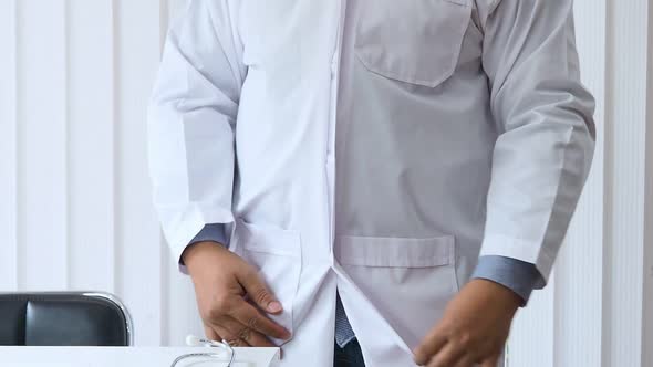 A doctor is wearing a gown before meeting the patient.