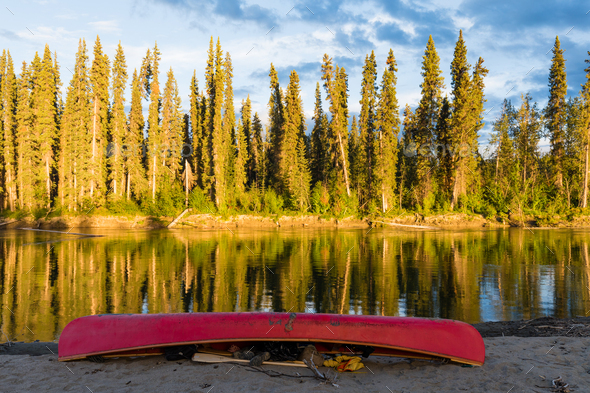 Red canoe on shore of Nisutlin River Yukon Canada - Stock Photo - Images