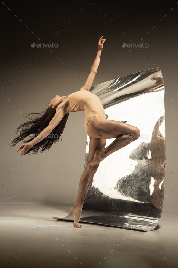 Young and stylish modern ballet dancer on brown background
